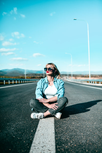 可爱的金发女人坐在高速公路中间图片下载