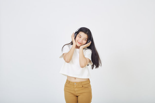 白色背景上戴着耳机的年轻可爱的女人图片下载