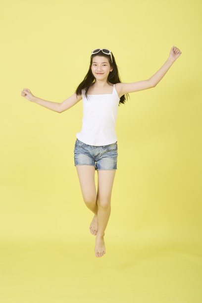 亚洲女孩快乐和跳跃在明亮的黄色背景半空中图片下载