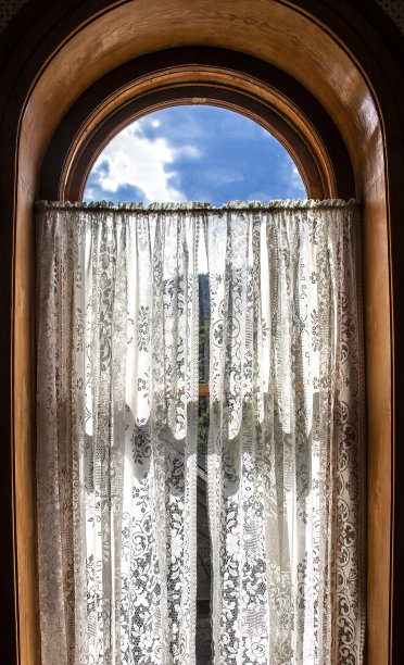 美丽的深木制拱形窗户显示蓝色的天空与花边窗帘图片下载