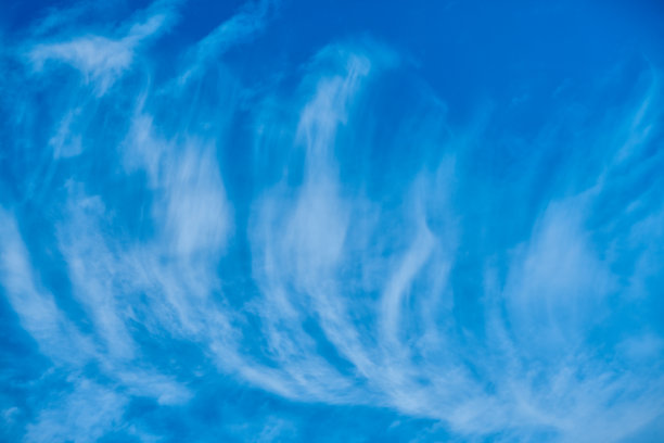 在夏天阳光明媚的日子里，高白色的缕缕卷云被风吹大，覆盖着深蓝色的天空图片下载