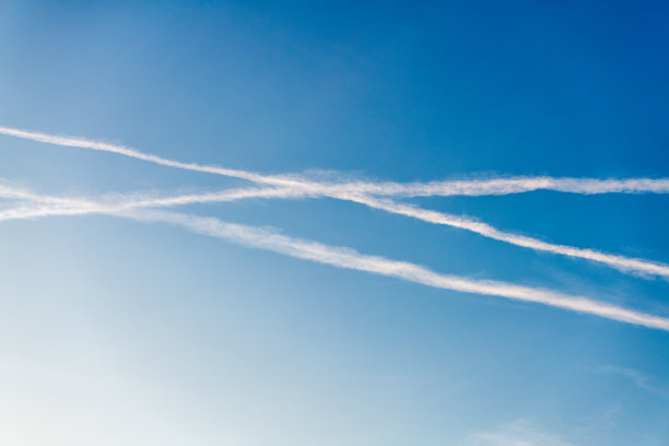 深蓝色的天空中有几道白色的凝结痕迹图片下载