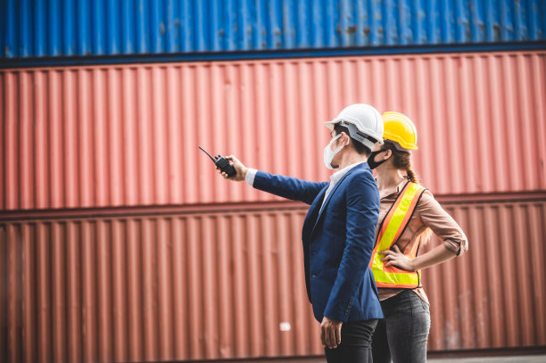 商人、高管和工程师戴医用口罩和头盔，同时检查工业工厂和仓库，为国际航运企业进出口的概念图片下载