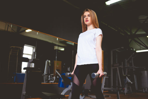 在体育馆拿着哑铃的体育女孩图片下载