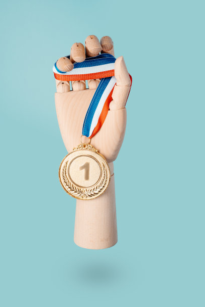 一只木制的手在蓝色的背景上举着一枚金牌。奖励和胜利理念。本空间图片下载