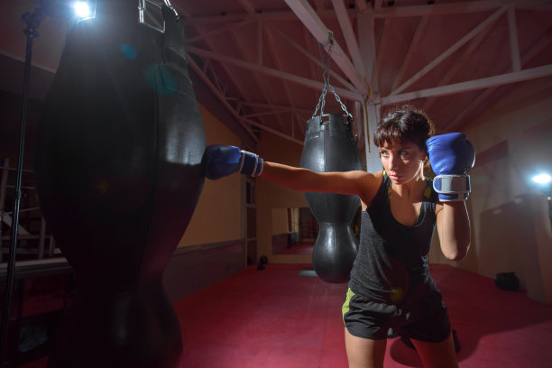 一名年轻的白人女子在健身房积极训练，戴着拳击手套在拳击袋前做拳击练习图片下载