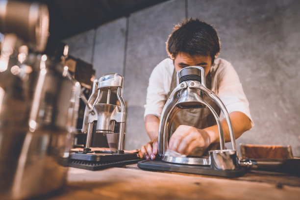 专业的咖啡师在经典的咖啡馆里制作新鲜咖啡的热饮，一杯咖啡色香气的热意式浓缩咖啡，为早上提供咖啡因饮料，咖啡豆和早餐背景图片下载