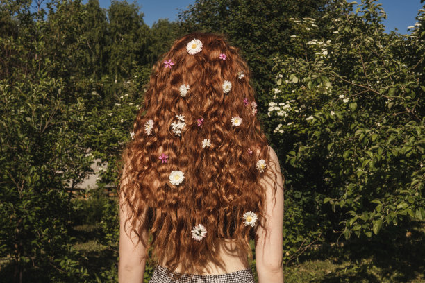 后视图年轻女孩与花的头发。图片下载