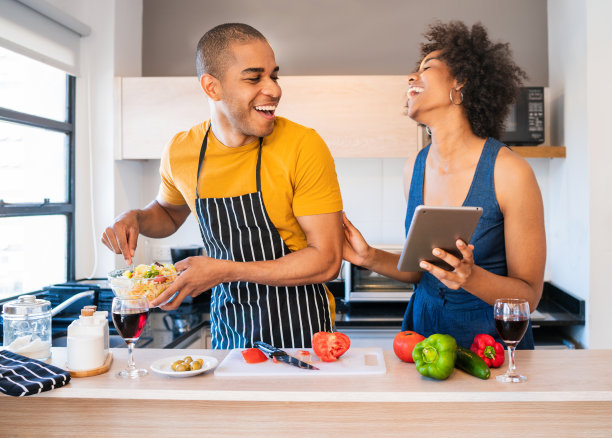 一对拉丁夫妇在厨房做饭时使用平板电脑。图片下载