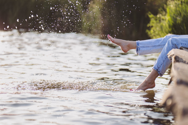 阳光下，穿着浅蓝色牛仔裤的女孩在湖上玩水。图片下载