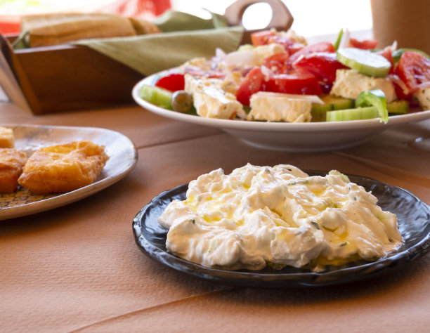 希腊伯罗奔尼撒半岛度假小镇Methana的餐桌上摆着希腊沙拉、酸奶黄瓜、烤奶酪和自制葡萄酒图片下载