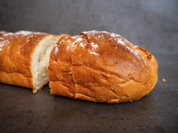 灰色的水泥桌上放着新鲜面包，特写。用刀切了一整条面包。健康食品和传统烘焙理念。图片下载