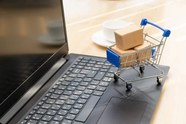 金属铬推车，盒子的背景是一个黑色的笔记本电脑和一个咖啡杯在工作的木桌上图片下载