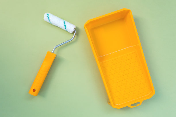 新油漆滚轮和黄色油漆托盘在柔和的绿色背景图片下载