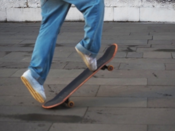 在滑板上表演把戏的青少年的腿。模糊的照片图片下载