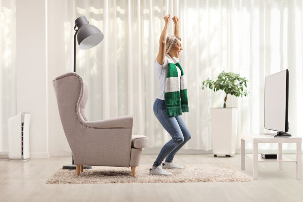 随便的年轻女子在家看比赛和欢呼与围巾图片下载