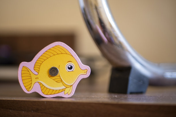 一种儿童玩具，用黄色的木头做成鱼的形状，放在铁的背景上图片下载