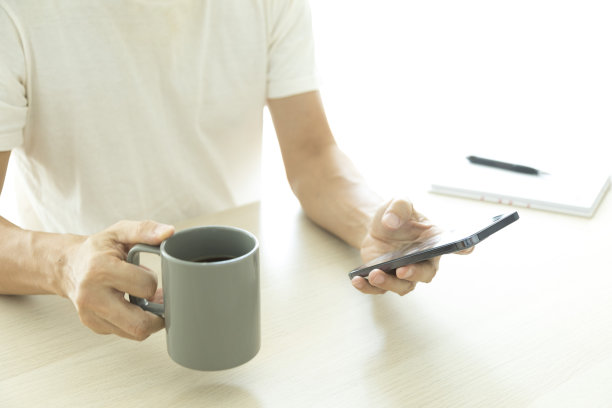 年轻男子在家里使用智能手机的特写。图片下载