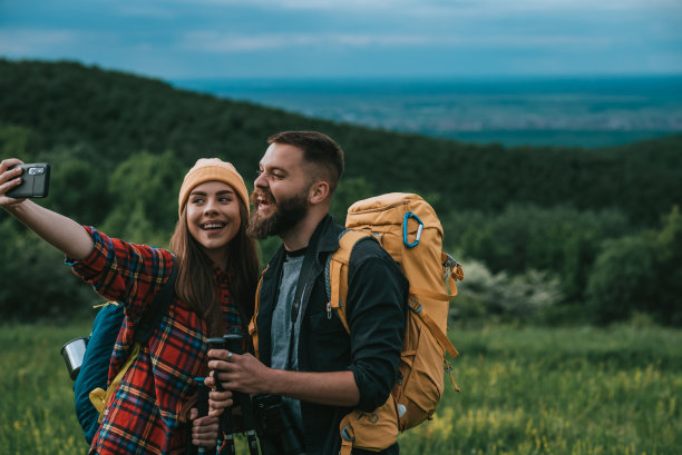 徒步旅行者一边用智能手机自拍，一边用登山杆在大自然中行走图片下载