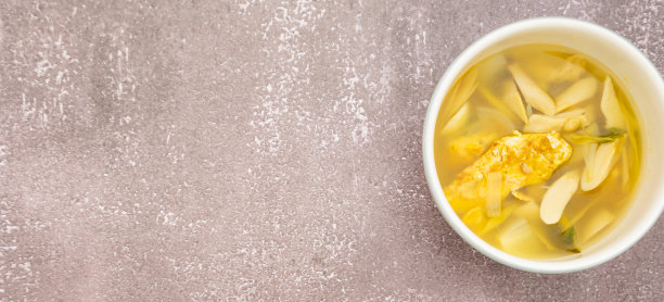 右中心的框架，软冬阴汤与蛋卷，蘑菇，高良姜，柠檬草在木桌子框架上的白色碗，软冬阴汤与蛋卷，蘑菇，高良姜，柠檬草在石头桌子上的白色碗图片下载