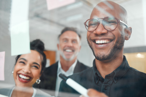 这张照片拍摄的是一群商人在办公室的玻璃墙上用笔记进行头脑风暴图片下载