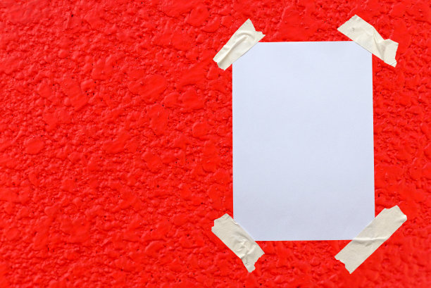 用胶带把白纸贴在红墙上。图片下载