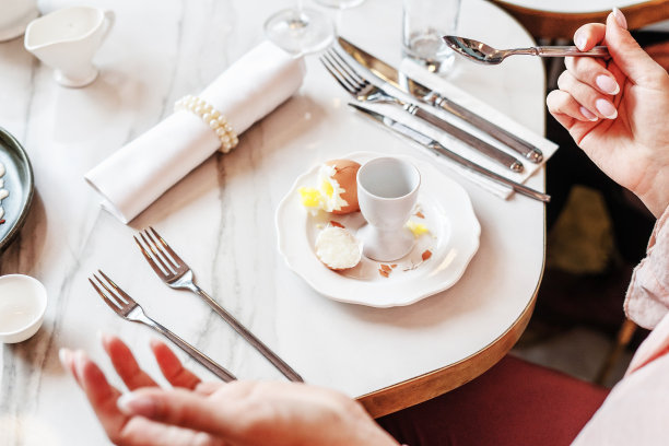 一个女人在餐馆里剥鸡蛋当早餐。有选择性的重点图片下载