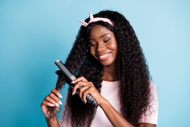 美丽闪亮的非洲女人的照片穿粉红色的t恤看手手臂头发直发孤立的蓝色背景图片下载