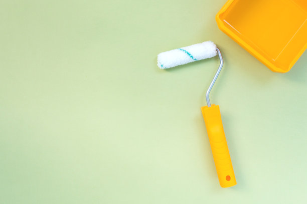 新油漆滚轮和黄色油漆托盘在柔和的绿色背景图片下载