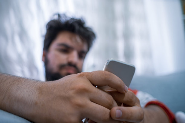 智能手机的选择性焦点和年轻疲惫的男人上网的低角度图片下载