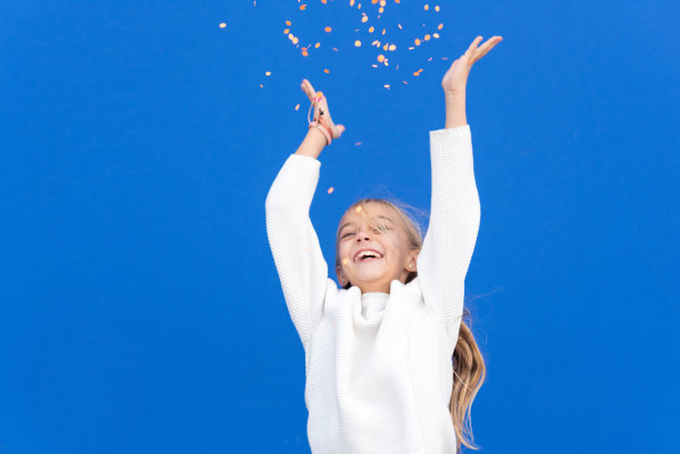 心满意足的女孩在飞舞的五彩纸屑中微笑。高质量的照片图片下载