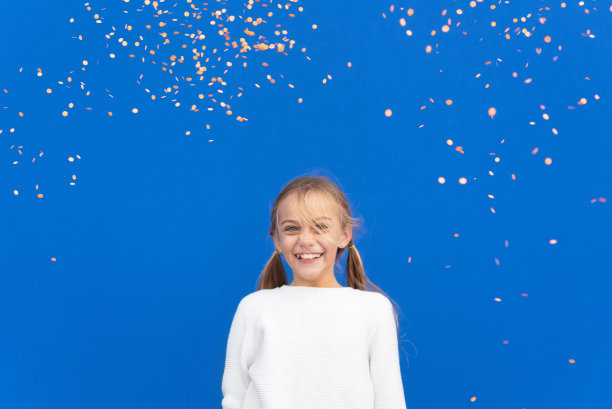 心满意足的女孩在飞舞的五彩纸屑中微笑。高质量的照片图片下载