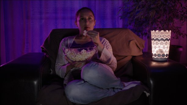 一个坐在沙发上看电视的女人。图片下载