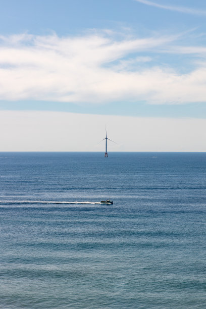 一艘渔船从海上的风力涡轮机前经过图片下载