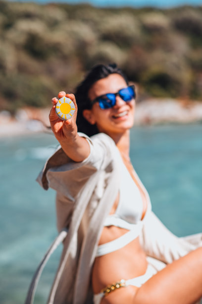 美丽的女人在海滩上抱着卵石与太阳图片图片下载