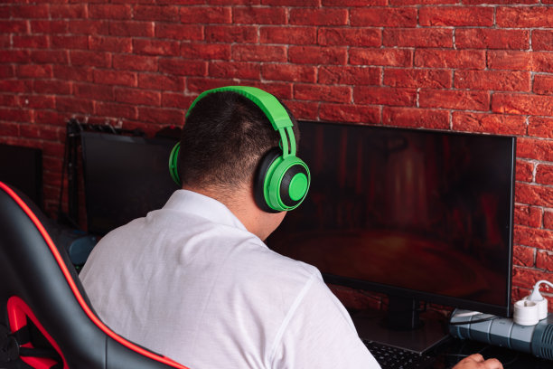 戴着绿色耳机在电脑上玩游戏的家伙图片下载