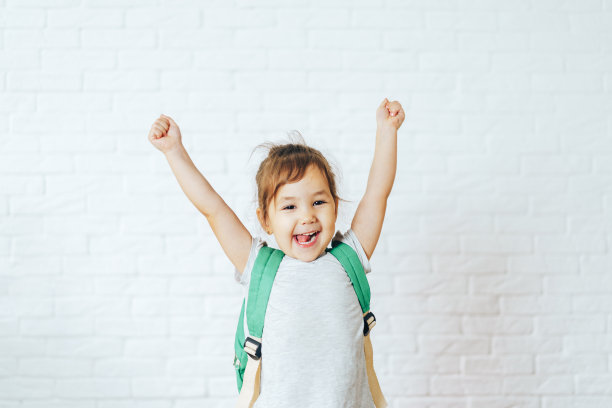 快乐的孩子在白色的背景前举起双手图片下载