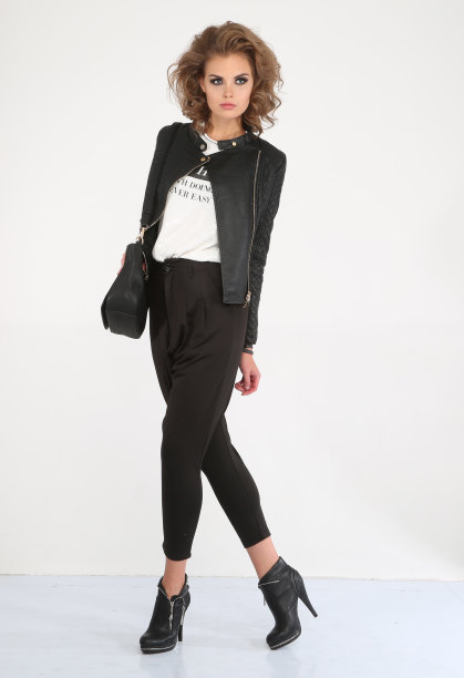年轻漂亮的女人穿着皮夹克，白色衬衫和黑色裤子前面的白色背景。图片下载