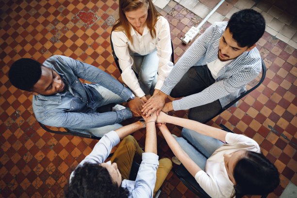 俯视各色人手牵着手围成一圈，双手堆叠图片下载