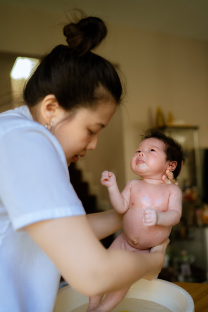 母亲在洗澡后给刚出生的婴儿洗澡。图片下载