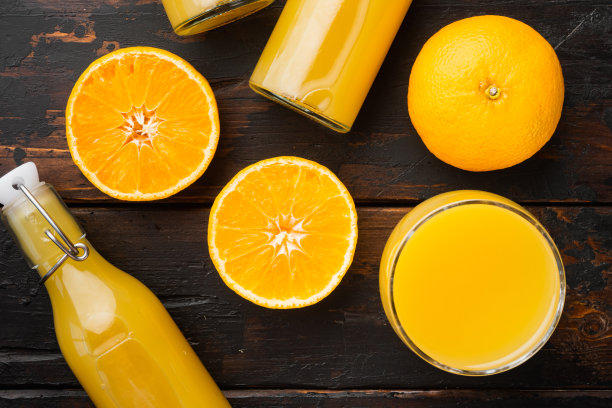 鲜橘汁的玻璃罐，在旧的深色木桌的背景上，俯视图平放图片下载
