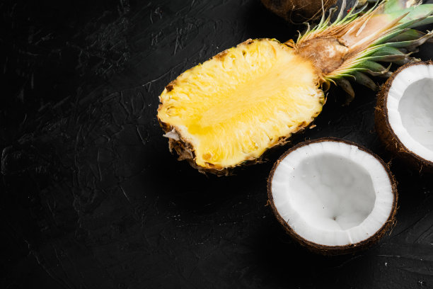 以热带水果、菠萝、椰子为素材，以黑色的深色石桌为背景，平放俯视图，并留有文字复制空间图片下载