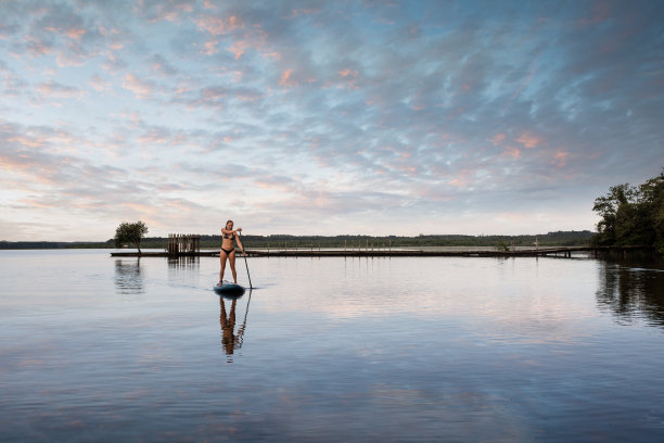漂亮的年轻女子在湖上划桨图片下载