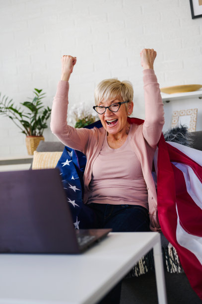 一位美国老太太在看比赛，拿着一面美国国旗为自己的球队加油。图片下载