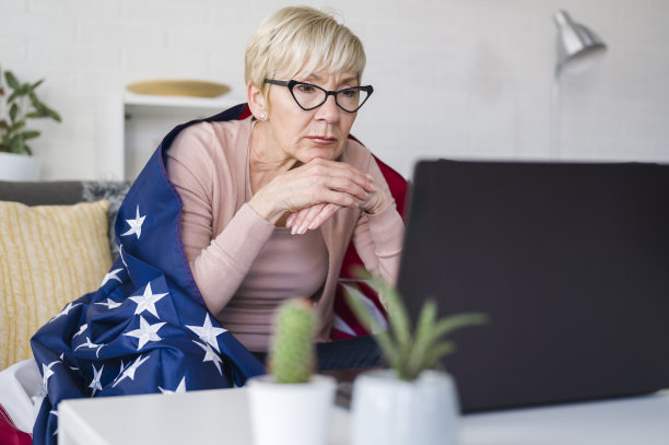 一位美国老太太在看比赛，拿着一面美国国旗为自己的球队加油。图片下载