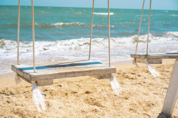 秋千与一个木制的座位，对着蓝色的大海图片下载