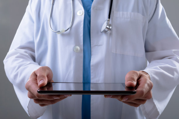 白人男性医生腹部使用片剂，孤立在灰色背景上图片下载