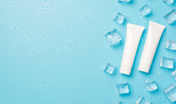 上面的照片是透明的冰块和两个小的白色奶油管孤立的蓝色背景与空白图片下载