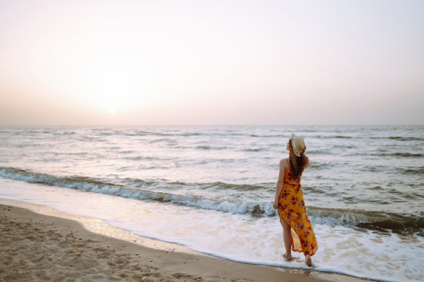 年轻女子享受美丽的日落，宁静的海洋自然在旅行假期。图片下载