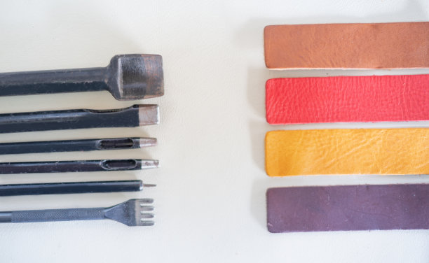 缝制皮革制品的工具。手工钱包，皮带，包在白色棉布衣服的背景图片下载